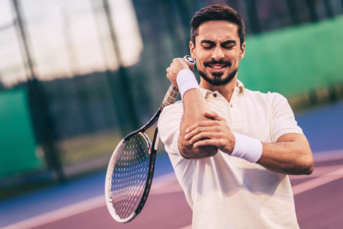 Man playing tennis with a hurt elbow